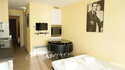 a room with a kitchen with a table and a tv at Appartement 607, vue mer, 4 personnes By Palmazur Vacances in Cannes