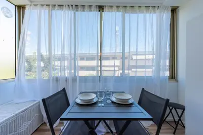 a dining room table with chairs in front of a large window at Appartement bord de mer in Cannes