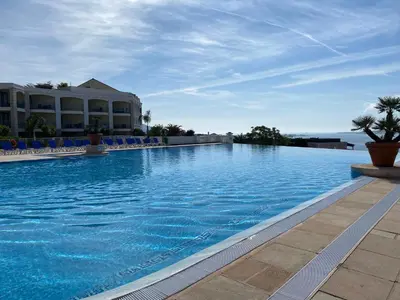 a large swimming pool with blue chairs and a building at Les Ingres By SCLS Locations in Cannes