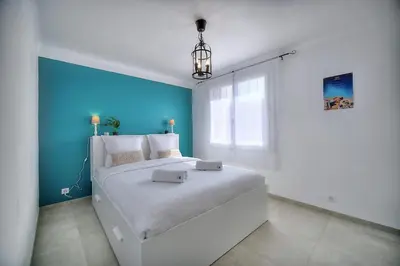 a bedroom with a large bed with a blue wall at IMMOGROOM - Renovated - Loggia - Clear view - Parking common - AC - Wifi in Cannes