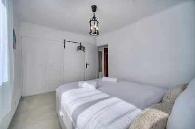 a white bedroom with a bed and a chandelier at IMMOGROOM - Renovated - Loggia - Clear view - Parking common - AC - Wifi in Cannes