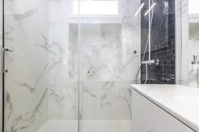 a white bathroom with a shower with a glass door at LB Vacation Rentals I Duplex Commandant Andre 65m2 I Casa d'Azur in Cannes