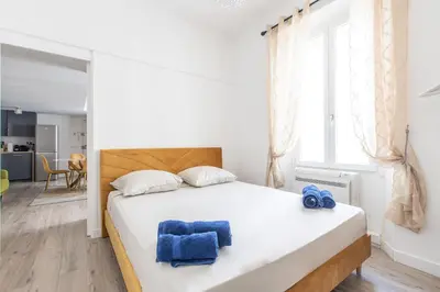 a bedroom with a large white bed with blue towels on it at LB Vacation Rentals I Duplex Commandant Andre 65m2 I Casa d'Azur in Cannes