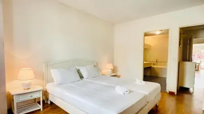 a bedroom with a white bed with two tables and two lamps at Cannes : superbe terrasse rue d'Antibes in Cannes