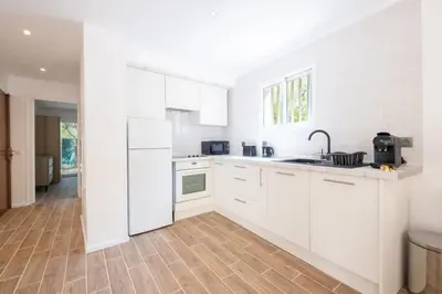 a kitchen with white cabinets and a wooden floor at 2-Bedroom Apartment with Garden in Cannes