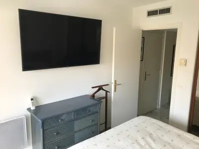 a bedroom with a blue dresser and a flat screen tv on a wall at ÉVÈNEMENTS CANNES in Cannes