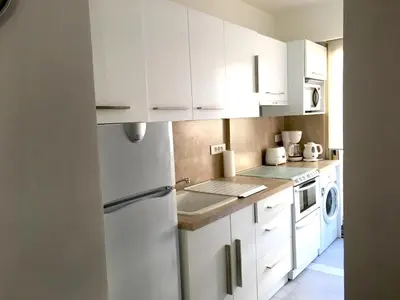 a kitchen with white cabinets and a white refrigerator at Palais Lumière in Cannes