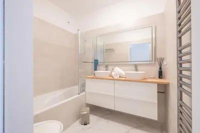 a bathroom with two sinks and a tub and a mirror at RARE! Exquisite 2-bd Apartment Facing the Sea in Cannes