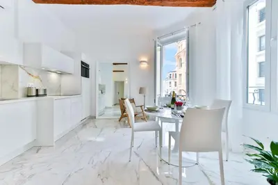 a white kitchen and dining room with a table and chairs at Alba apartment antibes street, by Welcome to Cannes in Cannes
