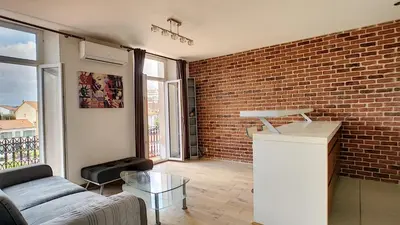 a living room with a couch and a brick wall at Superbe appartement vue dégagée sur des jardins in Cannes