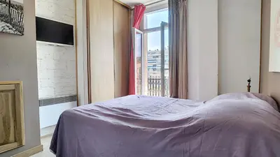 a bedroom with a bed and a large window at Superbe appartement vue dégagée sur des jardins in Cannes