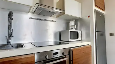 a kitchen with a sink and a microwave at Superbe appartement vue dégagée sur des jardins in Cannes