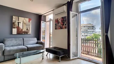 a living room with a couch and a large window at Superbe appartement vue dégagée sur des jardins in Cannes