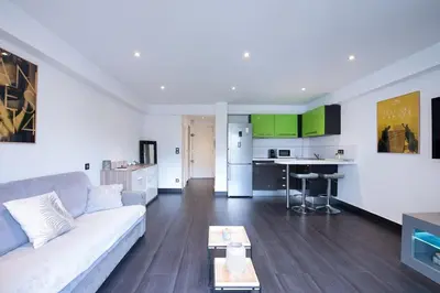 a living room with a couch and a kitchen at LE VENITIA studio raffiné avec balcon mignon, pour votre séjour à deux in Cannes