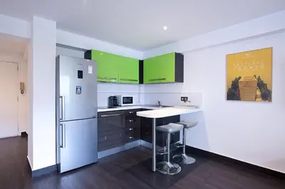 a kitchen with green cabinets and a white refrigerator at LE VENITIA studio raffiné avec balcon mignon, pour votre séjour à deux in Cannes