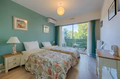 a bedroom with two beds and a desk and a window at LE CARDIFF avec grand balcon, piscine et parking, un fabuleux appartement familial en basse Californie in Cannes