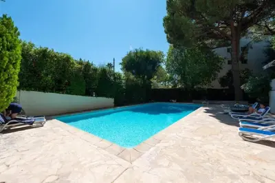 a swimming pool with two lounge chairs in a yard at LE CARDIFF avec grand balcon, piscine et parking, un fabuleux appartement familial en basse Californie in Cannes