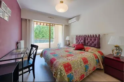 a bedroom with a bed and a desk and a window at LE CARDIFF avec grand balcon, piscine et parking, un fabuleux appartement familial en basse Californie in Cannes