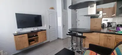 a kitchen with a table and a tv on a wall at Cannes Hoche Apartment in Cannes