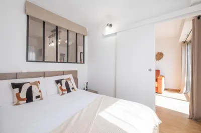 a bedroom with a white bed and a mirror at Comfy apartment with residential swimming pool in Cannes