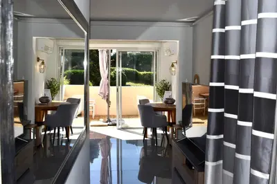 a dining room with a table and chairs and a mirror at Magnifique Appartement 2 pièces au calme in Cannes