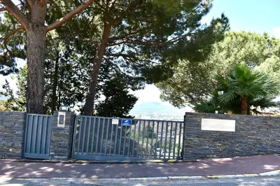 a fence with a gate in a park with trees at Magnifique Appartement 2 pièces au calme in Cannes