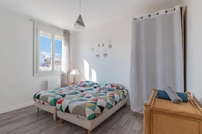 a bedroom with a bed with a colorful comforter and a window at Appt lumineux et spacieux au cœur de Cannes in Cannes