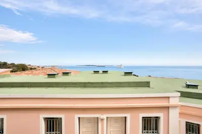 a pink building with a green roof and the ocean at Résidence Cannes Villa Francia - maeva Home - Appartement 3 pièces 7 personnes - Sélection MAE-0244 in Cannes