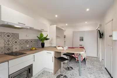 a kitchen with white cabinets and a wooden table at Cannes Hyper Centre climatisé in Cannes