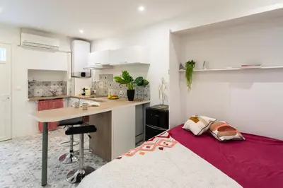 a bedroom with a bed and a kitchen with white cabinets at Cannes Hyper Centre climatisé in Cannes