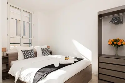 a white bedroom with a large bed and a window at Anzur YourHostHelper in Cannes