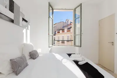 a bedroom with a white bed and a large window at Anzur YourHostHelper in Cannes