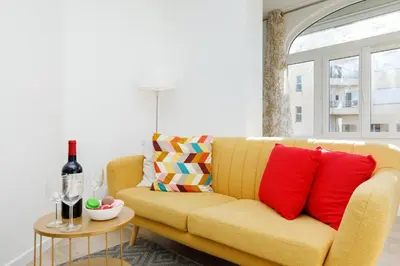 a yellow couch with red pillows in a living room at Lumière YourHostHelper in Cannes