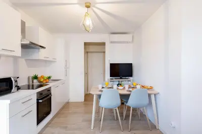 a kitchen with a table and chairs in a room at Lumière YourHostHelper in Cannes