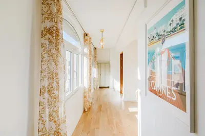 a hallway with white walls and a large window at Lumière YourHostHelper in Cannes