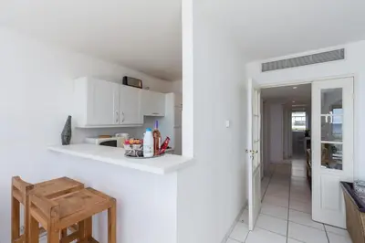a white kitchen with white cabinets and a hallway at Bright two bedroomed apartment on the beach in Cannes with huge terrace with fabulous sea views - 2001 in Cannes