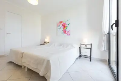 a white bedroom with a bed and a painting on the wall at Modern 3 bedroom 3 bathroom apartment for rent near Cannes Old Town walking distance to Palais - 2000 in Cannes