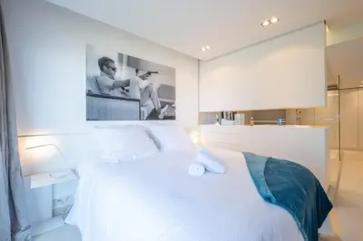 a bedroom with a white bed and a large mirror at Elegant 3-Room Apartment with Terrace Pool & Island Views in Cannes