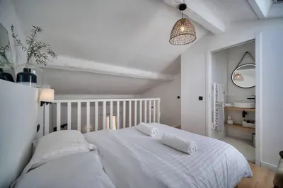 a bedroom with a white bed with two pillows on it at IMMOGROOM - Cosy - Renovated duplex - Close to the beach in Cannes