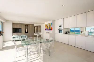a kitchen with white cabinets and a glass table and chairs at Incroyable 4P Vue Mer Panoramique in Cannes