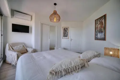 a white bedroom with a bed and a chair at Somptueux 2 chambres vue MER, TERRASSE, PARKING A2B232 in Cannes