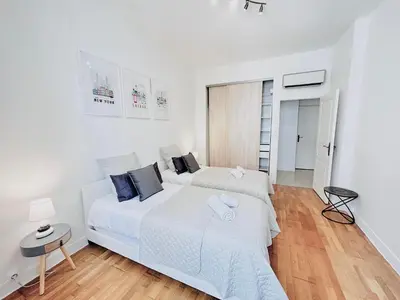 a white bedroom with two beds and a table at 2 Bedroom flat Cannes Center La Croisette Banane in Cannes