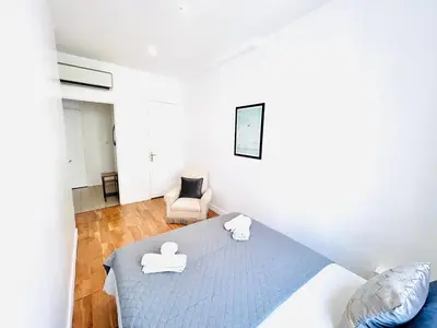 a white bedroom with a bed and a chair at 2 Bedroom flat Cannes Center La Croisette Banane in Cannes