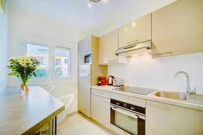 a kitchen with white cabinets and a vase of flowers at 2 bedroom luxury flat with Balcony Cannes Center in Cannes