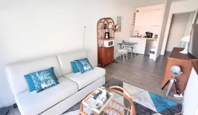 a living room with a white couch and a kitchen at L'ILOT avec balcon, mignon et charmant, un havre de paix au cœur du centre-ville in Cannes