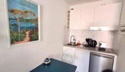 a kitchen with a blue table and a painting on the wall at L'ILOT avec balcon, mignon et charmant, un havre de paix au cœur du centre-ville in Cannes