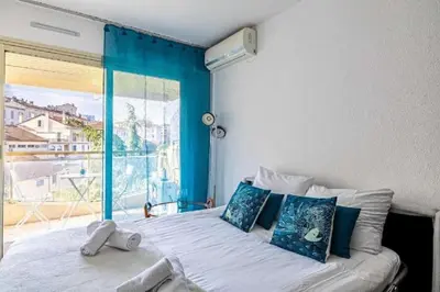 a bedroom with a bed with a large window at L'ILOT avec balcon, mignon et charmant, un havre de paix au cœur du centre-ville in Cannes