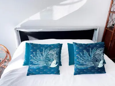 a bed with two blue pillows on it at L'ILOT avec balcon, mignon et charmant, un havre de paix au cœur du centre-ville in Cannes