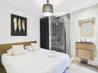 a bedroom with a large white bed and a shower at LE SPECTACULAIRE moderne et raffiné, idéalement situé à deux pas du Palais et plages in Cannes