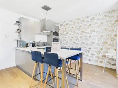 a kitchen with a white table and blue chairs at LE SPECTACULAIRE moderne et raffiné, idéalement situé à deux pas du Palais et plages in Cannes